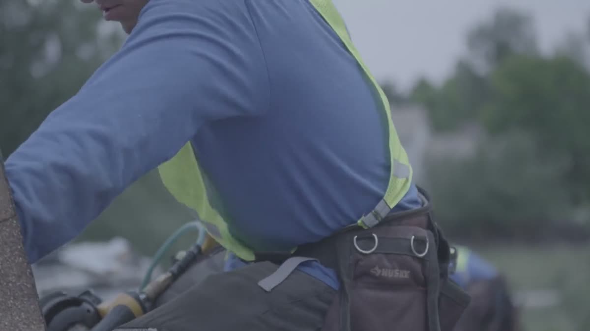Roofer secured with a safety harness during installation